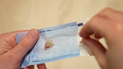 doctor puts two extracted wisdom teeth in a sterile bag and closes it securely for the client