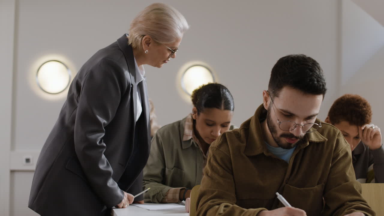 Students taking a test with a teacher supervising