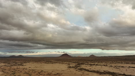 mojave desert an distant buttes with the tiny silhouette of a lone human walking in the vast landscape - ascending aerial view