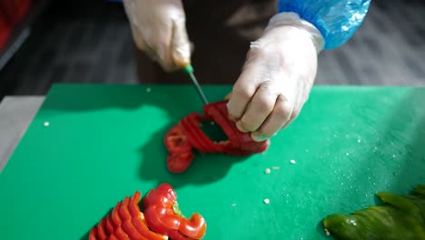 Cerca-De-La-Mano-Del-Chef-Cortando-Pimentón-Rojo-En-Una-Tabla-De-Cortar-De-Madera