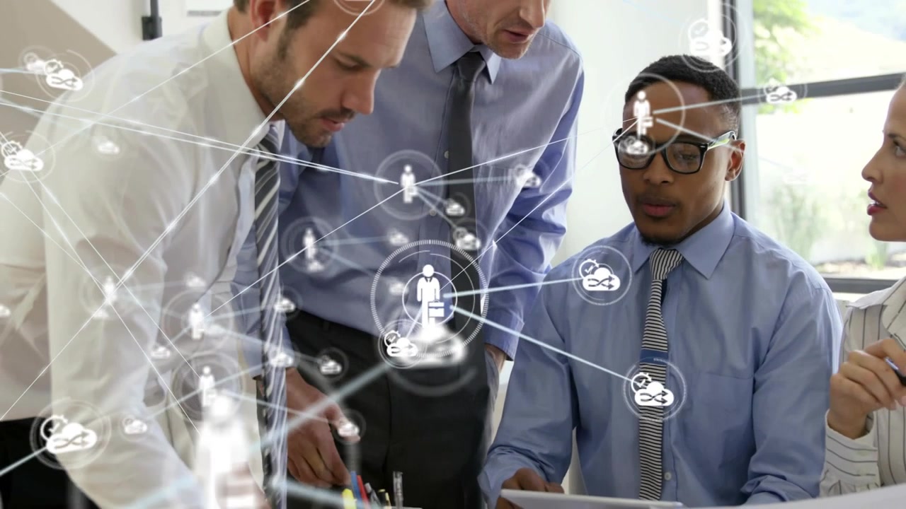 Business team pointing at desk devices, reviewing docs, causing network overlay linking cloud icons