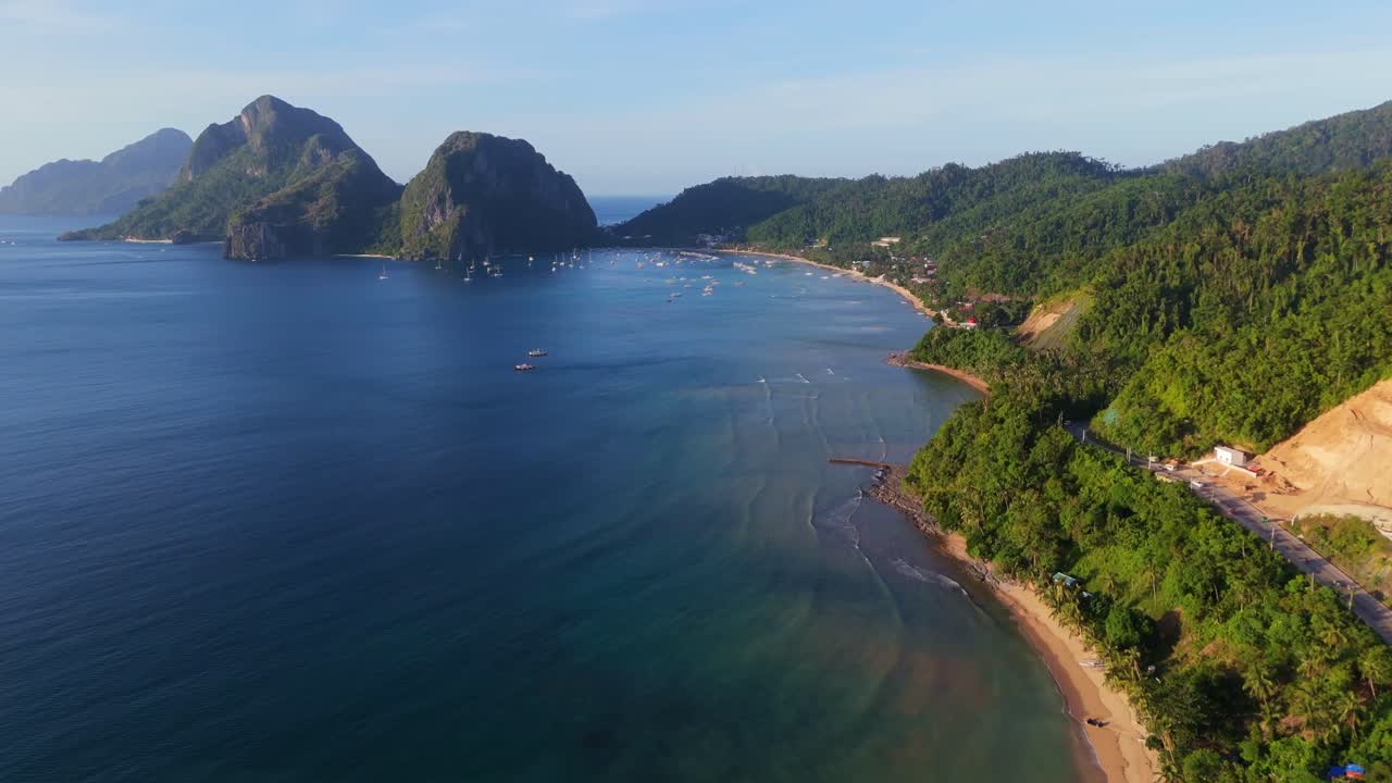 Cảnh quay drone điện ảnh từ trên cao về bãi biển cát trắng hoang sơ với thuyền truyền thống và vách đá vôi sừng sững ở El Nido, Palawan. Phong cảnh thiên đường nhiệt đới ở Philippines.