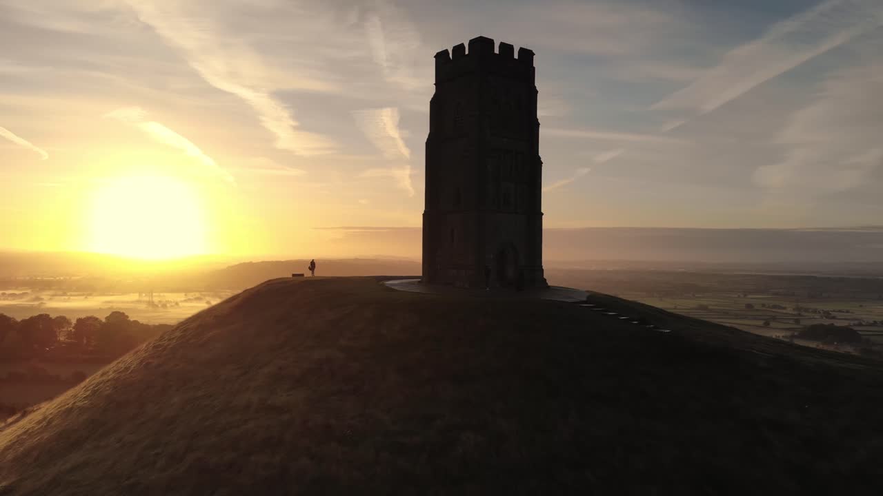 alejando imágenes aéreas del amanecer dorado sobre glastonbury tor, somerset