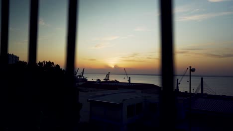 hafen sonnenaufgang lissabon morgendämmerung mit kranichsilhouette durch rostige zäune