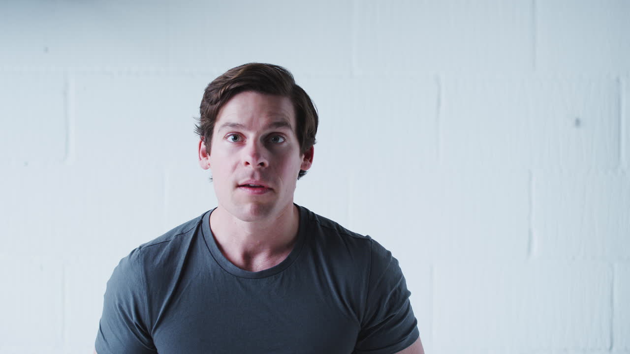 Studio Portrait Of Male Sports Fan Celebrating Against White Wall