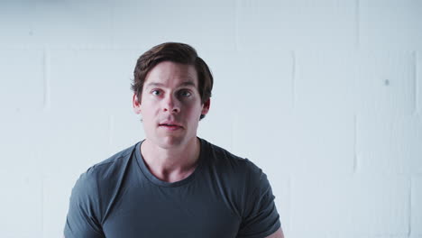 studio portrait of male sports fan celebrating against white wall