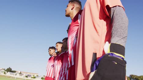 Video-of-diverse-group-of-football-players-standing-on-field-with-ball