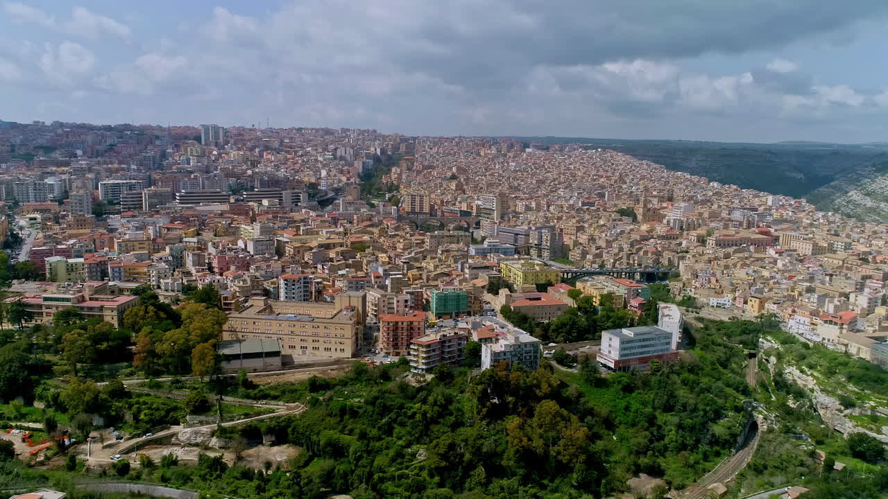 태양이 있는 흐린 날 시칠리아 섬에 있는 라구사의 도시 경관을 보여주는 공중 전망 - 전경에 공원이 있는 아름다운 이탈리아 옛 마을