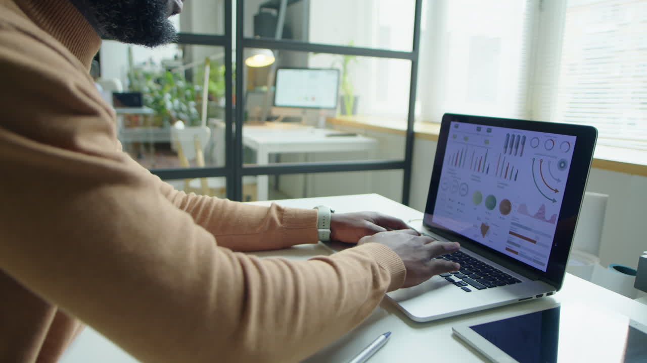 Black Businessman Working with Financial Report on Laptop