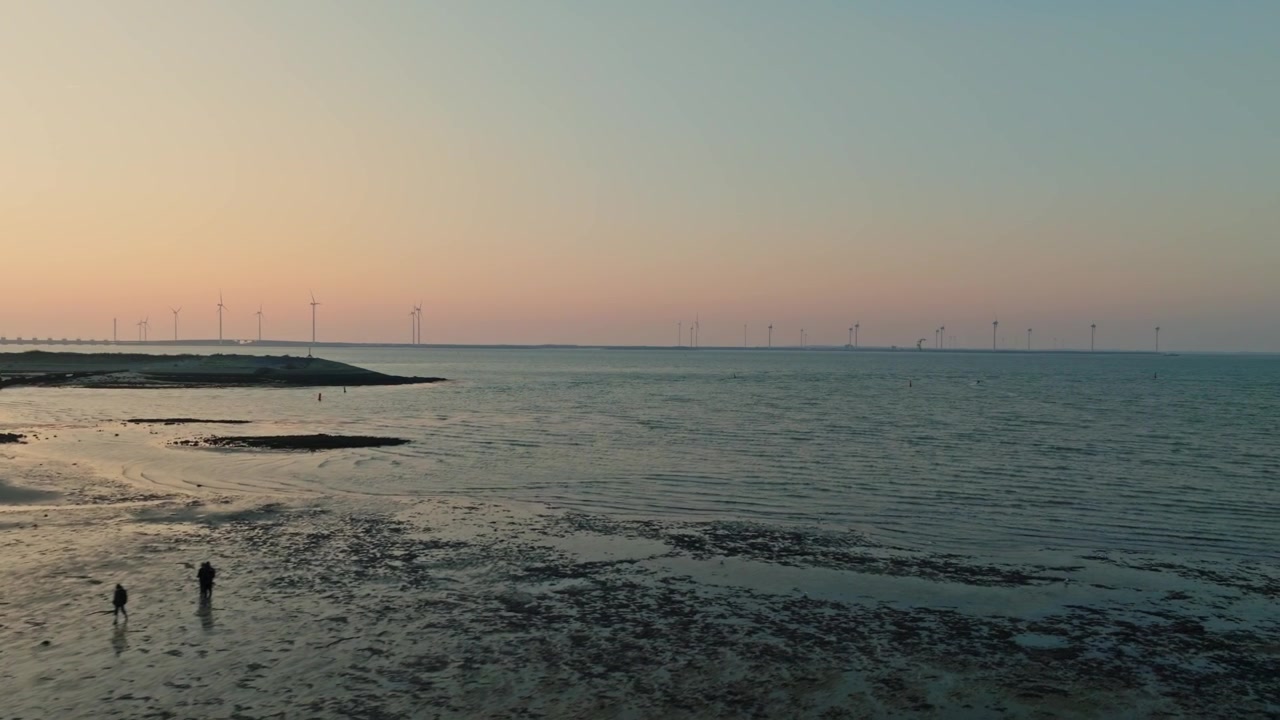 Ripresa con drone di una spiaggia durante la bassa marea al tramonto, che mostra la barriera anti-tempesta dell'Oosterschelde