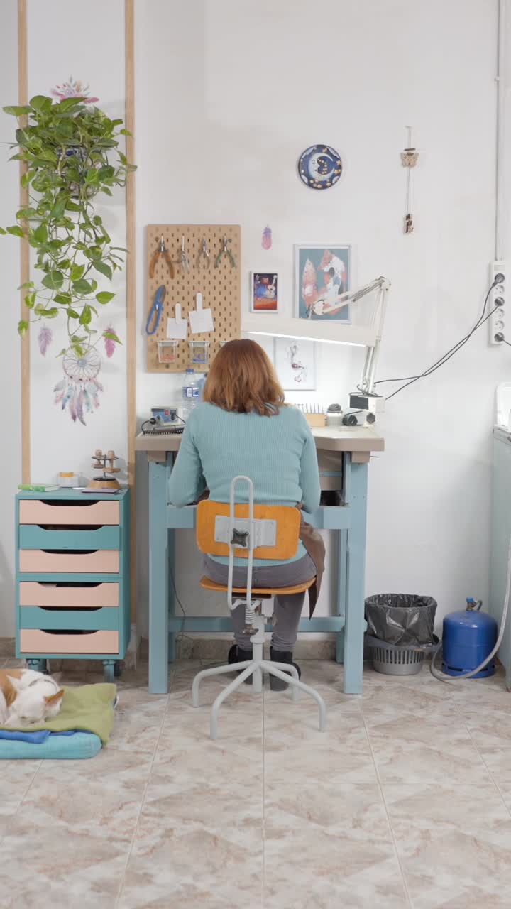 Woman working at a craft workbench in a bright workshop with a dog