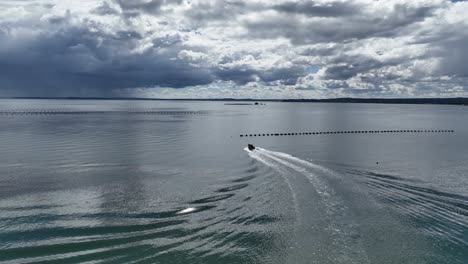 Aerial-View-Of-Speed-Boat-Going-Past-Offshore-Aquaculture-In-Puerto-Montt-Bay