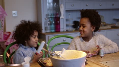 two children eating homemade cupcakes at table shot on r3d