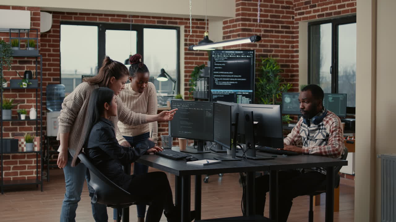 Mixed team of software engineers brainstorming ideas for new code library in front of computer screens