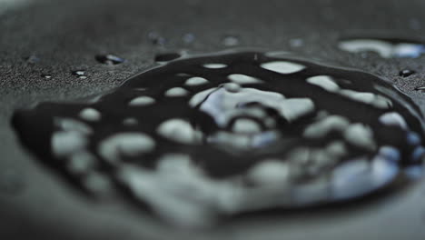 captura de gota de agua en cámara lenta en cámara macro de cierre cuando golpea vodní hladinu a pomalu se rozpustí do stran en placa de fondo oscuro con reflejo de luz