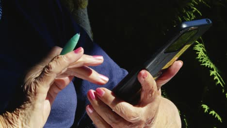 senior person sits outdoors using smartphone touchscreen technology