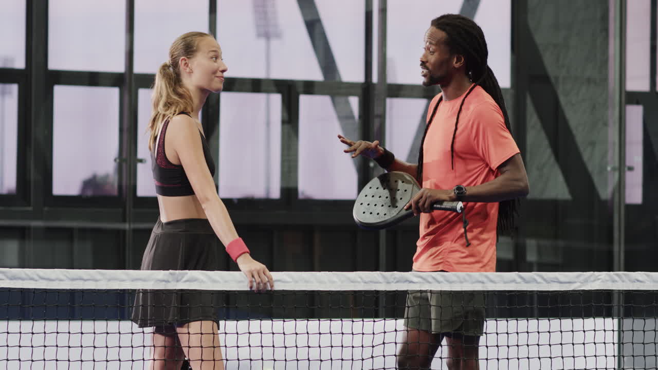 Padel diverse players discussing strategy on court, holding rackets, showing teamwork
