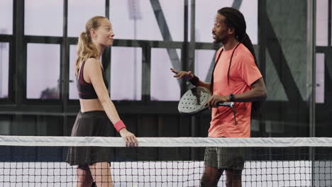 padel diverse players discussing strategy on court, holding rackets, showing teamwork