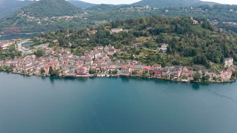 isola di san giulio on calm lake orta in italy, showcasing historic architecture with overgrown hills in the background, aerial view