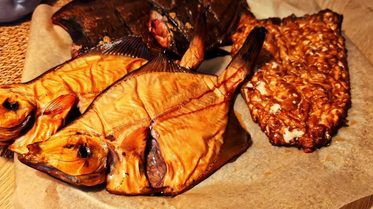 Smoked fish laid open and filleted, paper underneath on table in outdoor setting