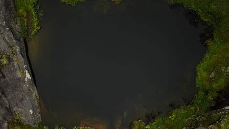 Vista-Anterior-Del-Profundo-Y-Oscuro-Lago-De-Montaña-Con-Orilla-Rocosa