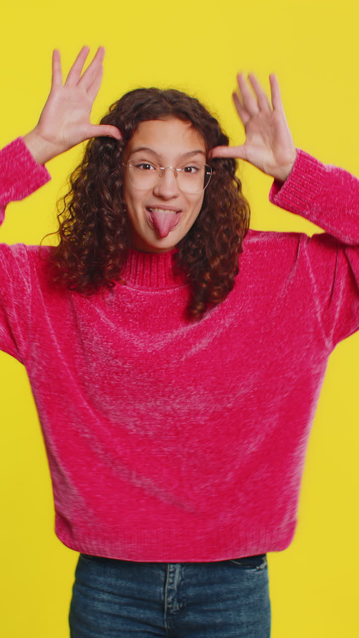 Cheerful funny bully girl showing tongue making silly faces fooling around joking teasing