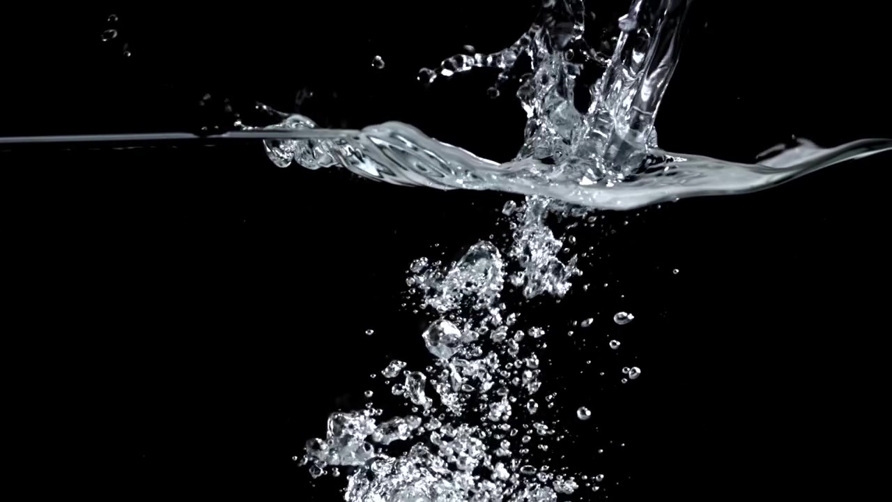 Acqua limpida che si versa e bolle al rallentatore su sfondo nero