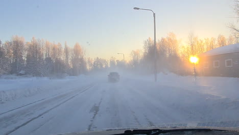 driving through small town on icy winter road during golden sunset, pov shot