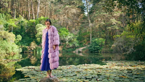 beautiful forest nymph standing on stone at nature lake. fantasy model posing