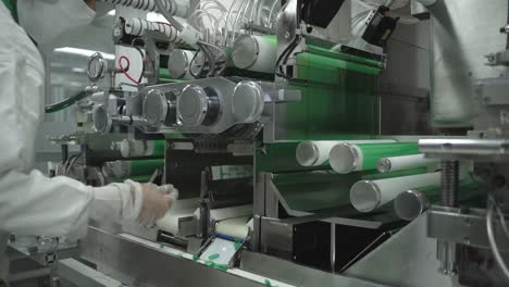 automated machinery with quality inspector checking the capsules in pharmaceutical plant.