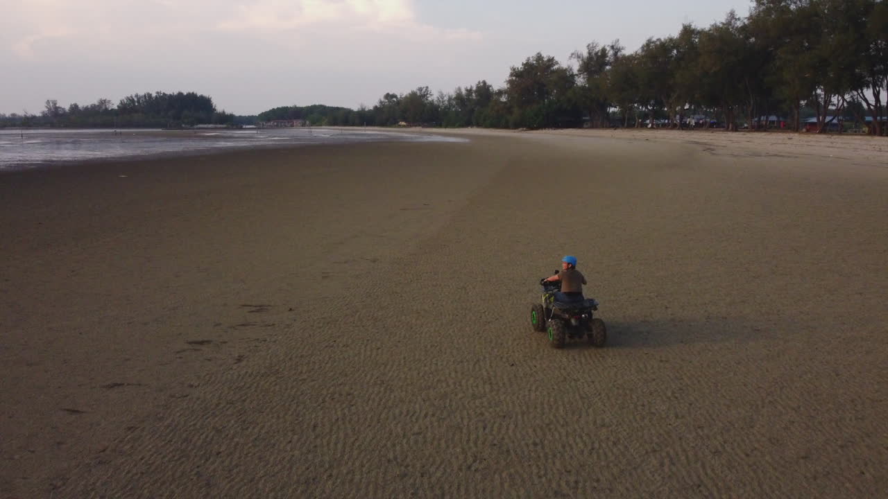 Guidatore di quad che percorre il lungomare sulla spiaggia di Bagan Lalang, Malesia