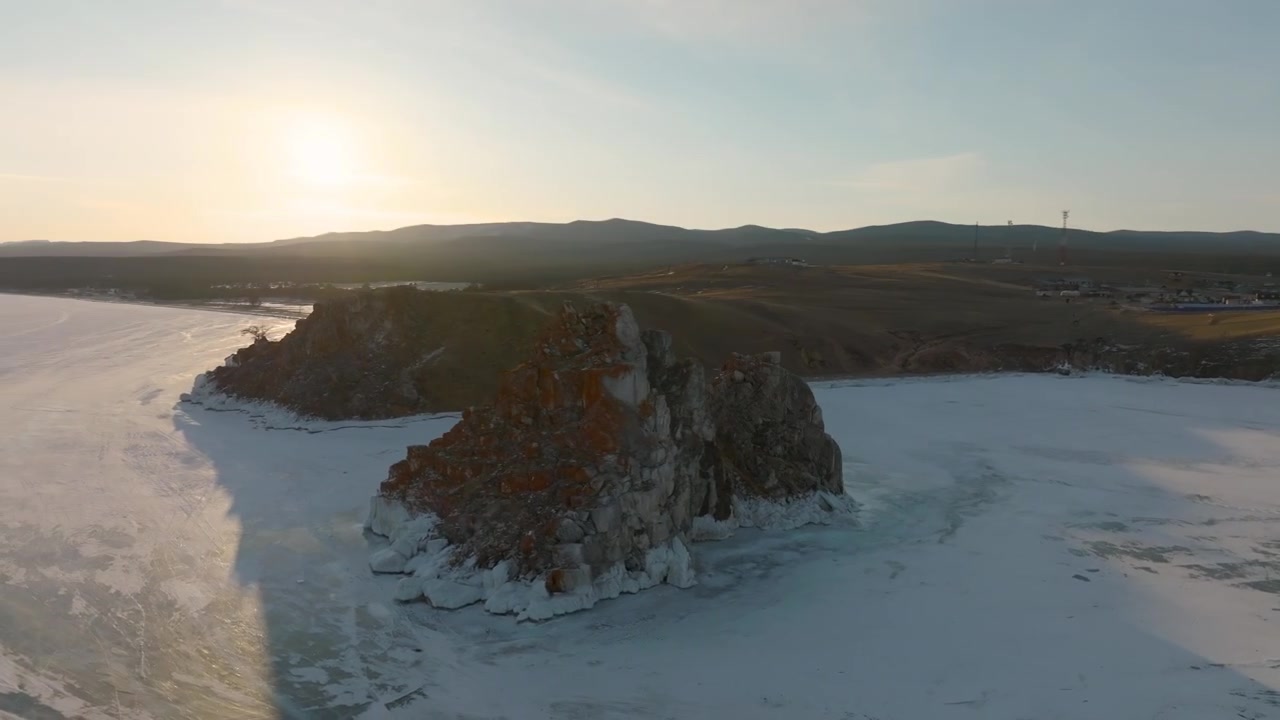 Ilmakuvaa Shamanka-kalliosta Baikaljärven Olkhonin saaren jäätyneellä rannalla, Irkutskin alueella, Venäjällä, lämpimässä auringonlaskun valossa ja jäisine pintoineen.