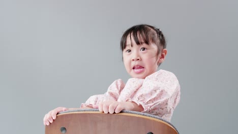 child playing on the chair at home and looking at camera