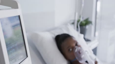 African-american-female-patient-with-oxygen-mask-lying-in-bed-in-hospital-room,-slow-motion