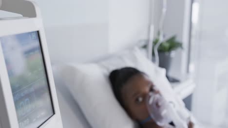 african american female patient with oxygen mask lying in bed in hospital room, slow motion