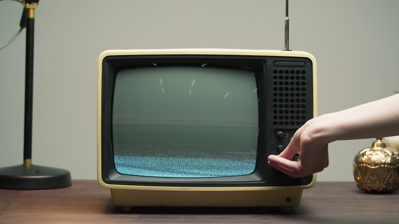 Mano che sintonizza un televisore vintage con schermo disturbato.