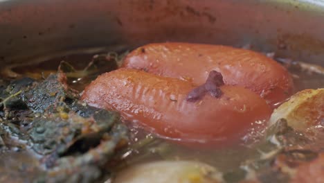 red pepper boiling in a delicious vegetable soup with onions and spices - extreme close up