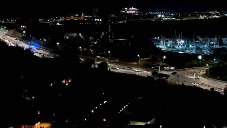 ambulance with constant blue lights zooms racing past cars on highway above bridge in tropical city at night, drone of curacao