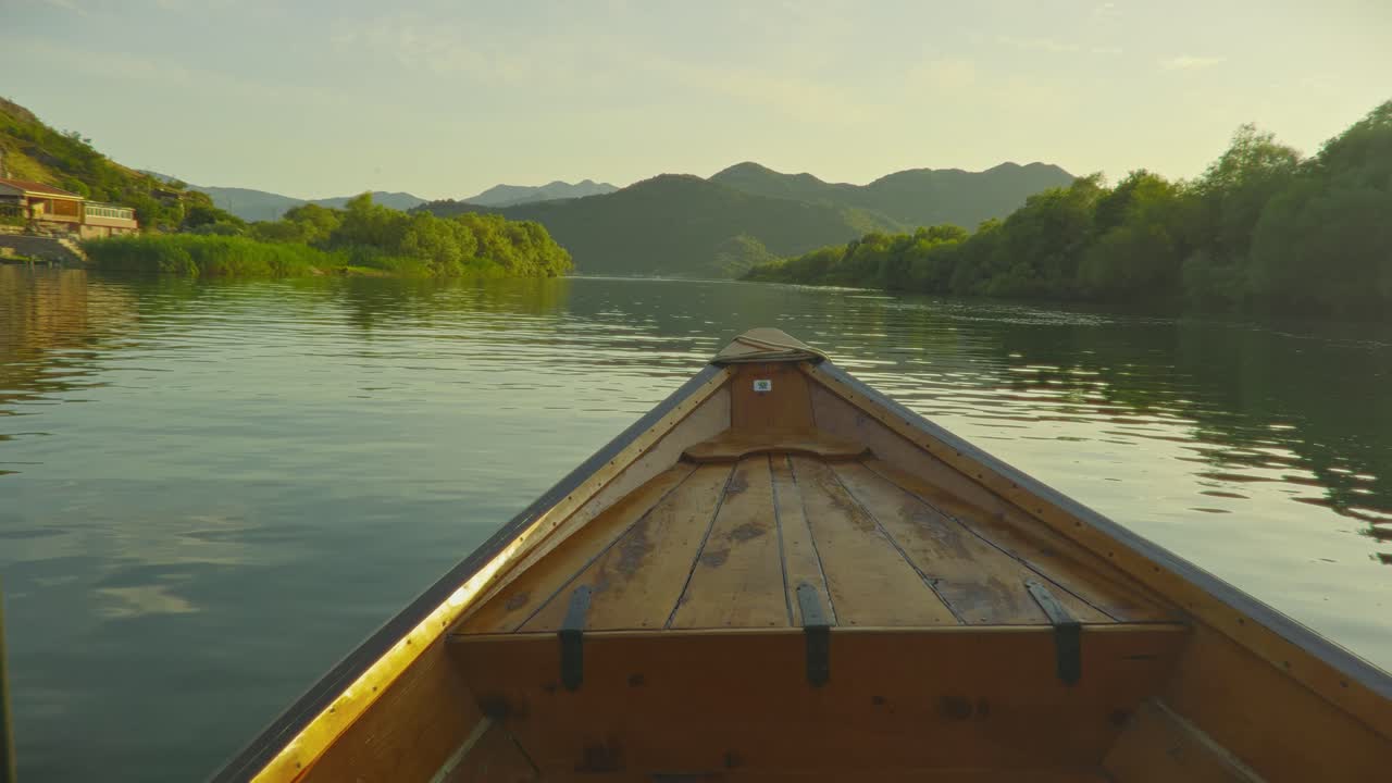 Sunset view from a wooden boat on Skadar Lake, Montenegro, with mountain backdrop