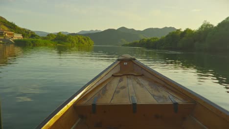 sunset view from a wooden boat on skadar lake, montenegro, with mountain backdrop