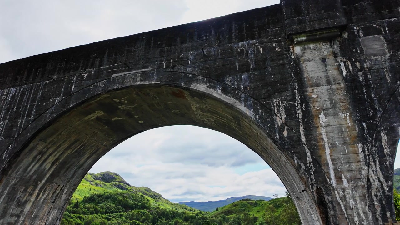 Beautiful low angle pan of the arches of the Glenfinnan Viaduct, also known as the bridge from Harry Potter, in Scotland on a sunny, summer day