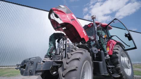 farmer mechanic repairing tractor. open tractor hood, engine. repair agricultural technology