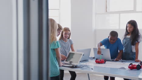 students with female teacher in after school computer coding class learning to program robot vehicle