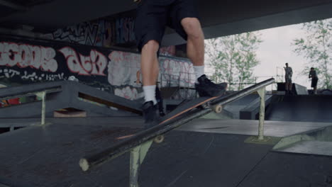 Millennial-man-performing-extreme-tricks-on-rail-at-urban-skate-park.