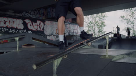 millennial man performing extreme tricks on rail at urban skate park.