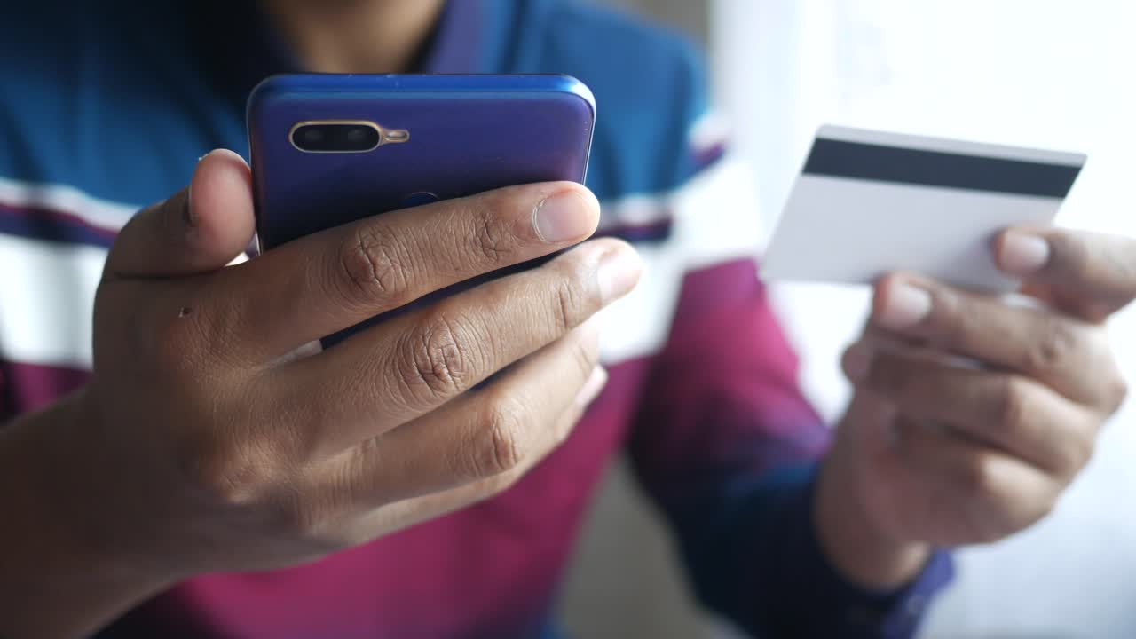 persona que utiliza un teléfono inteligente y una tarjeta de crédito para el pago en línea