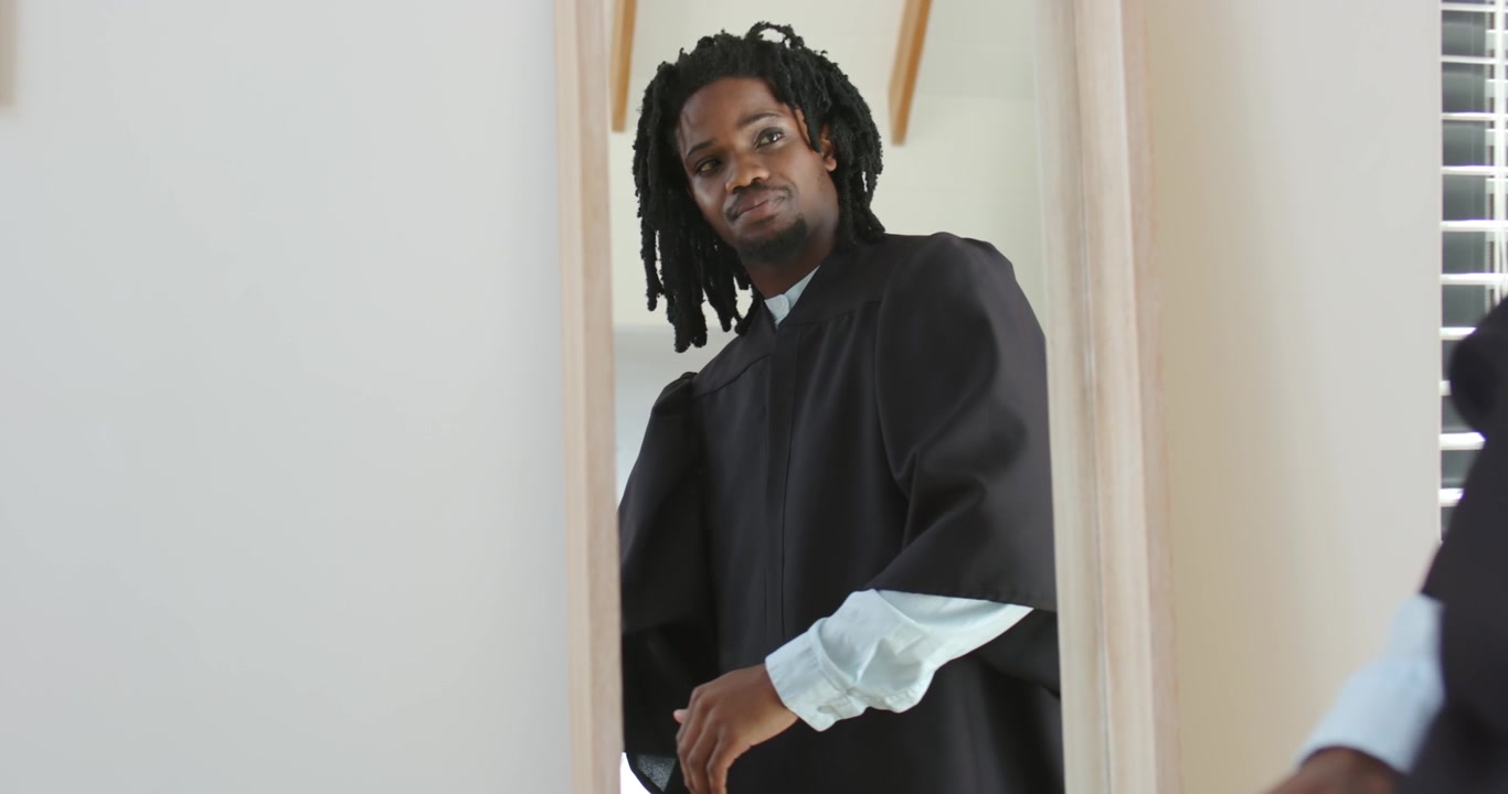 Homme afro-américain dans l'embrasure de la porte, ajustant ses poignets et attachant sa robe de chambre après un coup d'œil dans le miroir, vérifiant sa montre