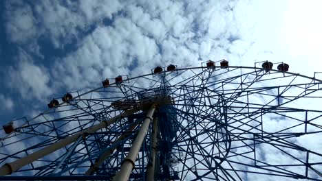 big ferris wheel slowly rotating, summer day in city park