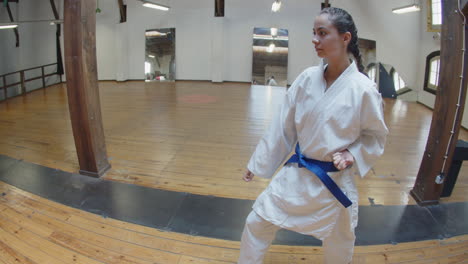 tracking shot of focused girl practicing karate movements in gym