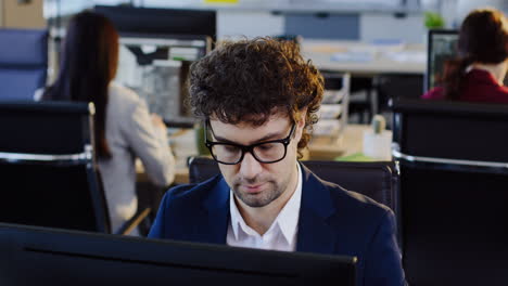 kaukasischer geschäftsmann mit brille, der im büro am computer arbeitet